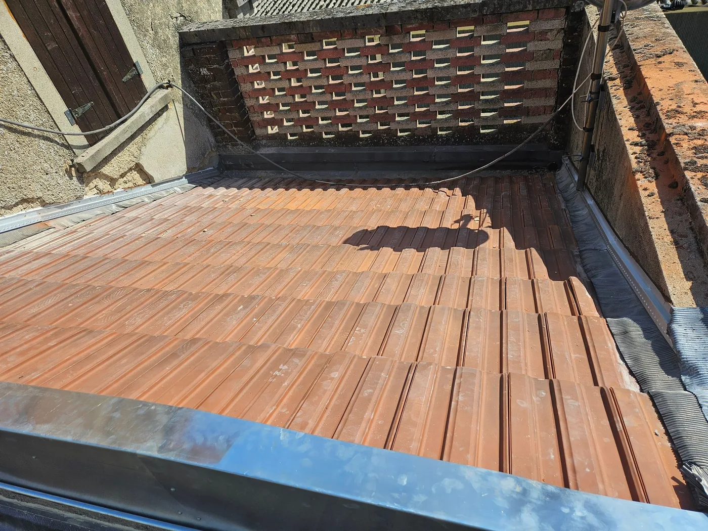 Couverture en tuiles terminée le long d'un chéneau en zinc neuf