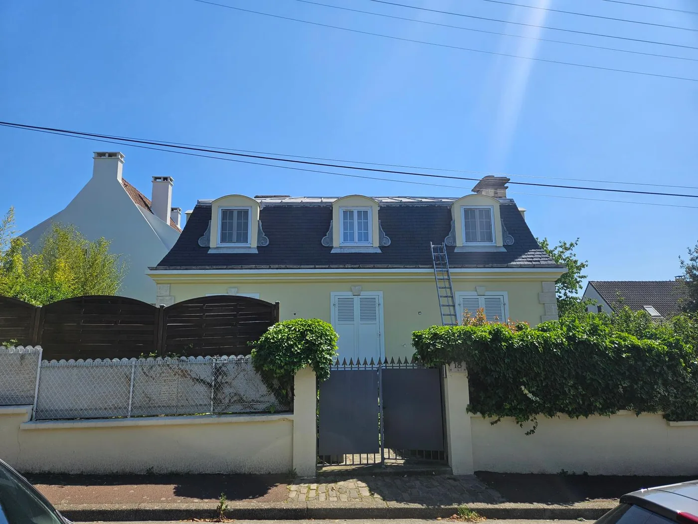 Maison mansardée et sa couverture en ardoise, échelle posée
