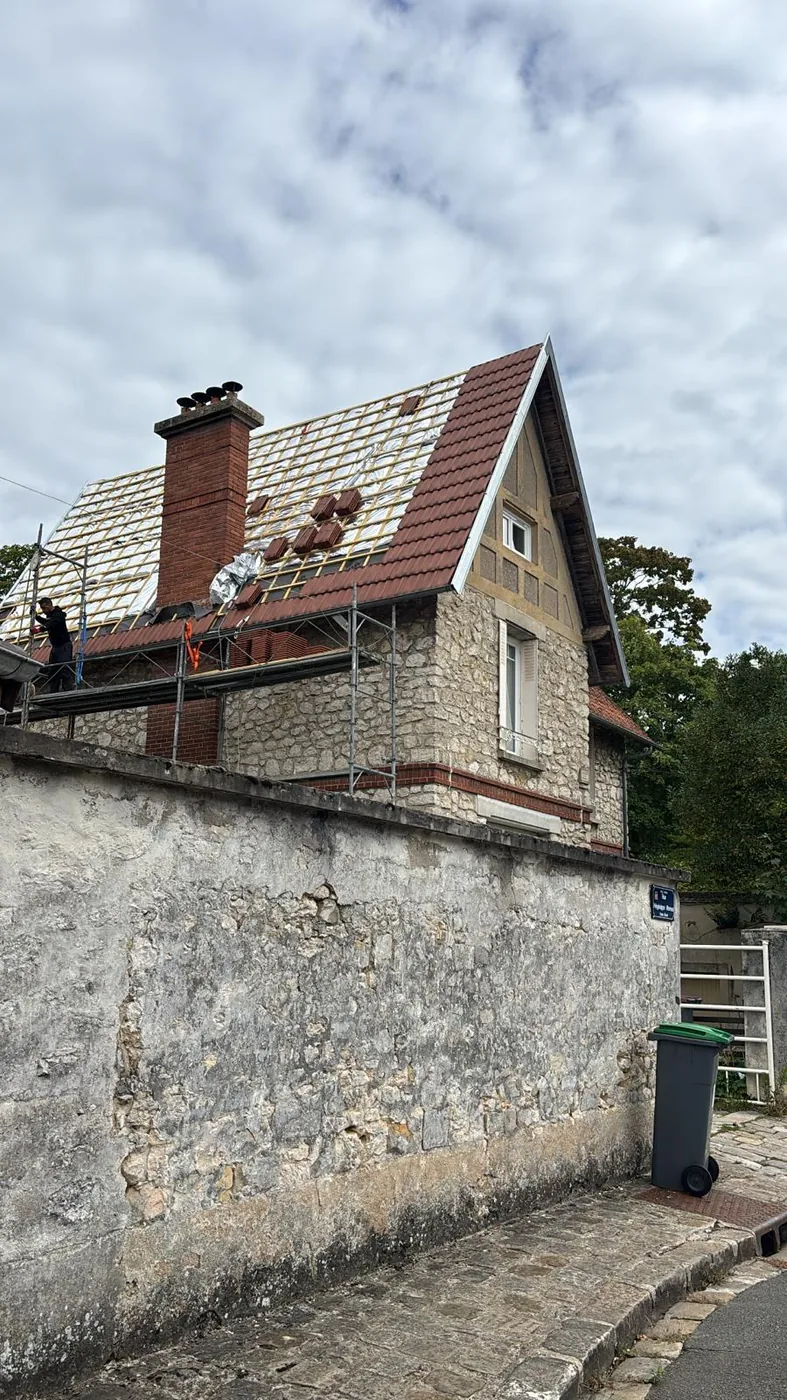 Maison ancienne derrière son mur de pierre, toiture en tuiles