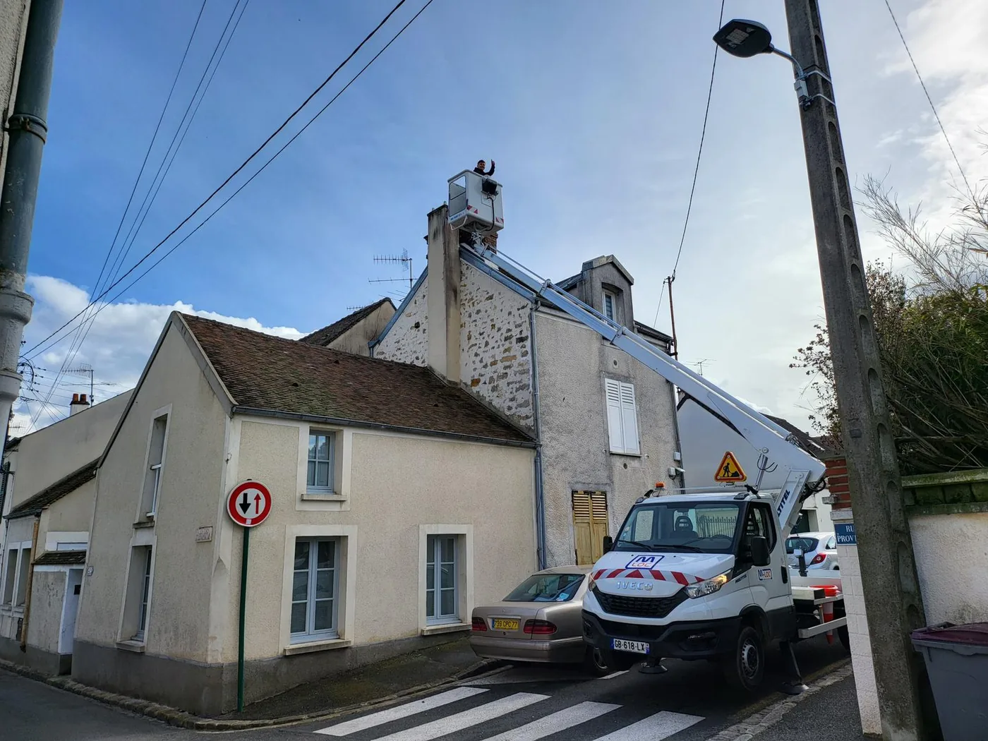 Rue de village, camionnette de chantier stationnée devant une maison en pierre